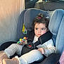 backseat, boots, buckle, car_interior, car_seat, child, cozy, curly_hair, headrest, infant_clothing, little_hands, onesie, plush_toy, portrait, safety, seat_belt, serious_expression, toddler, toy, window