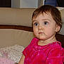 toddler, child, indoor, portrait, pink_dress, blanket, sofa, curly_hair, earrings, cute, young_child, seated, expression, face, person, home, cozy, clothing, soft_lighting, looking_away