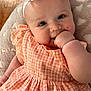 baby, infant, child, smile, face, headband, flower, dress, gingham, pattern, blanket, heart_pattern, hand, cheeks, skin, cute, happy, lying_down, indoors, wood_floor