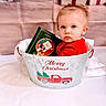 toddler, child, baby, bucket, christmas, holiday, gift, present, red_clothing, book, indoor, festive, decorations, face, portrait, cute, holiday_season, winter, smile, sitting