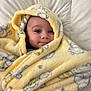 baby, bed, blanket, cartoon_print, child, comfort, cozy, cute, face, happy, human, indoors, infant, portrait, smile, soft, warm, white_background, wrapped, yellow