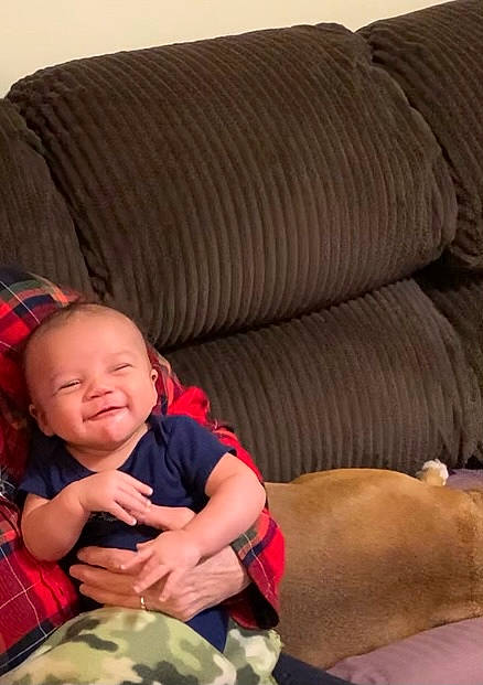 Liam is registered to the contest to win money with this photo: arm, baby, baby_toddler_clothing, child, comfort, couch, elbow, finger, grass, head, human_body, human_leg, knee, lap, pattern, person, skin, sleeve, thigh, toddler