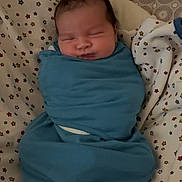 Amir joined the competition — help win amazing prizes! newborn, baby, swaddled, blanket, sleeping, infant, star_pattern, bed, bedding, cozy, child, face, resting, cute, soft_lighting, indoor, person, peaceful, head, wrapped