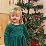 celebration, child, christmas_tree, decorations, dress, festive, floor, girl, green_dress, hair_tie, happy, holiday, indoor, lights, person, photos, seasonal, smile, wall, young_child
