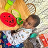 Rhett is registered to the contest to win money with this photo: toddler, child, booster_seat, dinosaur_pattern, table, wooden_table, plate, blueberries, bowl, spoon, food, meal, curtains, chair, pajamas, smile, face, indoor, home, happy