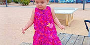 Abidi Amira participe au concours pour gagner de l'argent avec cette photo : toddler, child, dress, pink, outdoor, park, wooden_platform, walking, hair_buns, shoes, sneakers, buildings, trees, cars, sidewalk, daylight, person, playground, urban, happy