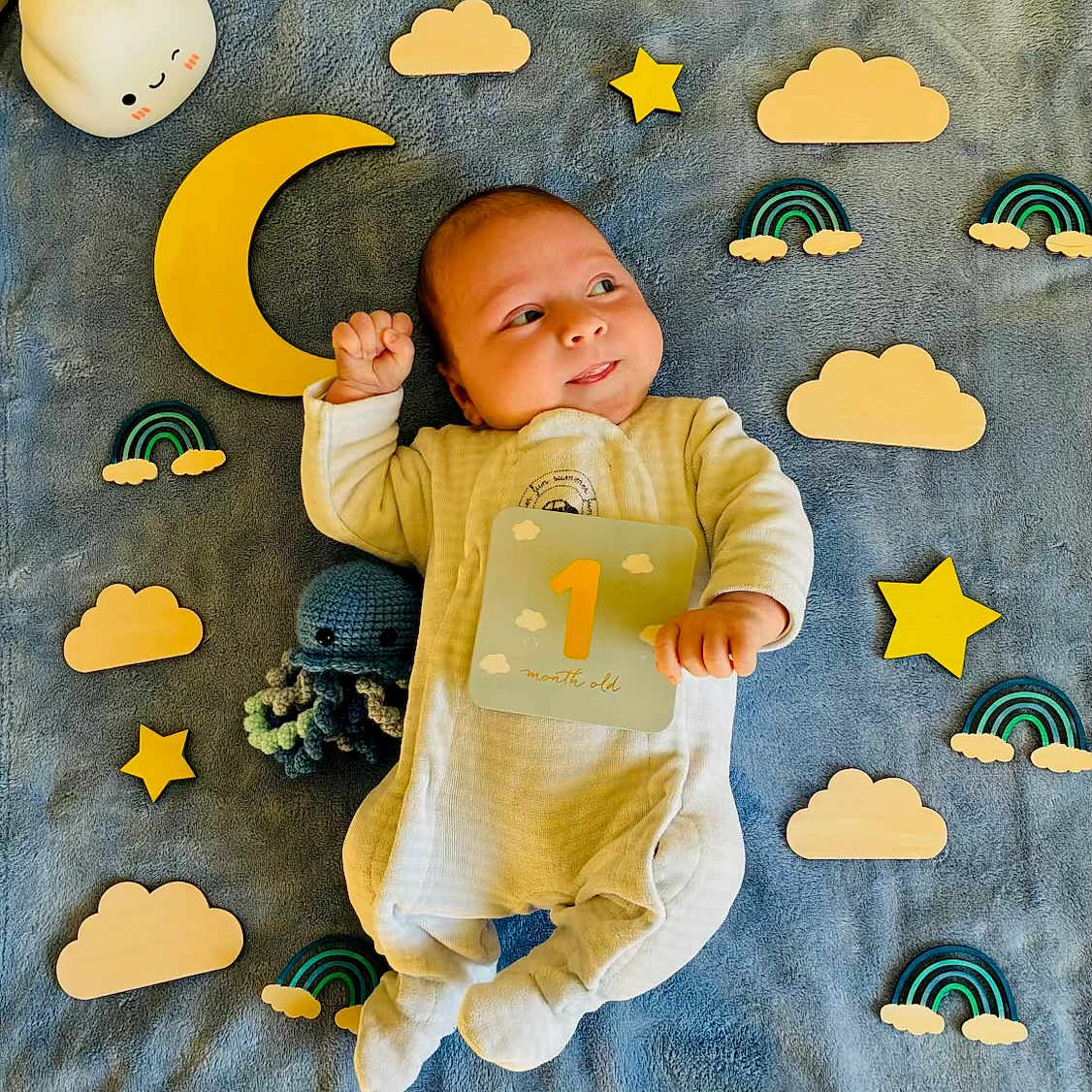 Owen a rejoint le concours — aidez-le/la à gagner de superbes lots ! baby, blanket, child, colorful, crocheted_toy, cute, happy, indoors, infant, lying_down, newborn, octopus, one_month_old, playful, portrait, smiling, soft_toys, wooden_clouds, wooden_rainbows, wooden_stars
