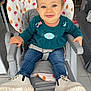 toddler, child, high_chair, smiling, blue_eyes, sweater, cat_design, jeans, boots, indoor, floor_tiles, furniture, playful, happy, seat_belt, home, patterned_fabric, cute, baby, person