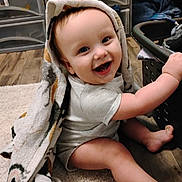 Royal joined the competition — help win amazing prizes! baby, child, smiling, towel, indoors, floor, laundry_basket, wooden_floor, carpet, happy, cute, playful, clothing, person, face, head, sitting, expression, blanket, home
