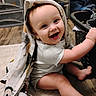 baby, child, smiling, towel, indoors, floor, laundry_basket, wooden_floor, carpet, happy, cute, playful, clothing, person, face, head, sitting, expression, blanket, home