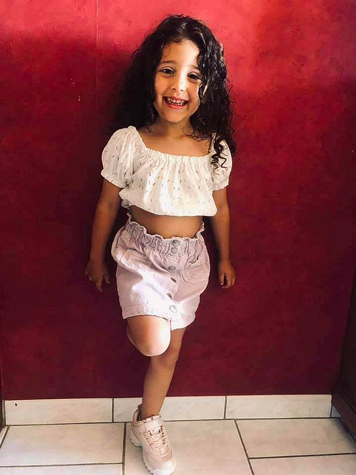 Mariana participe au concours pour gagner de l'argent avec cette photo : abdomen, black_hair, chest, face, footwear, hair, happy, head, human_body, jean_short, joy, knee, neck, person, pink, shoe, shorts, smile, t_shirt, thigh