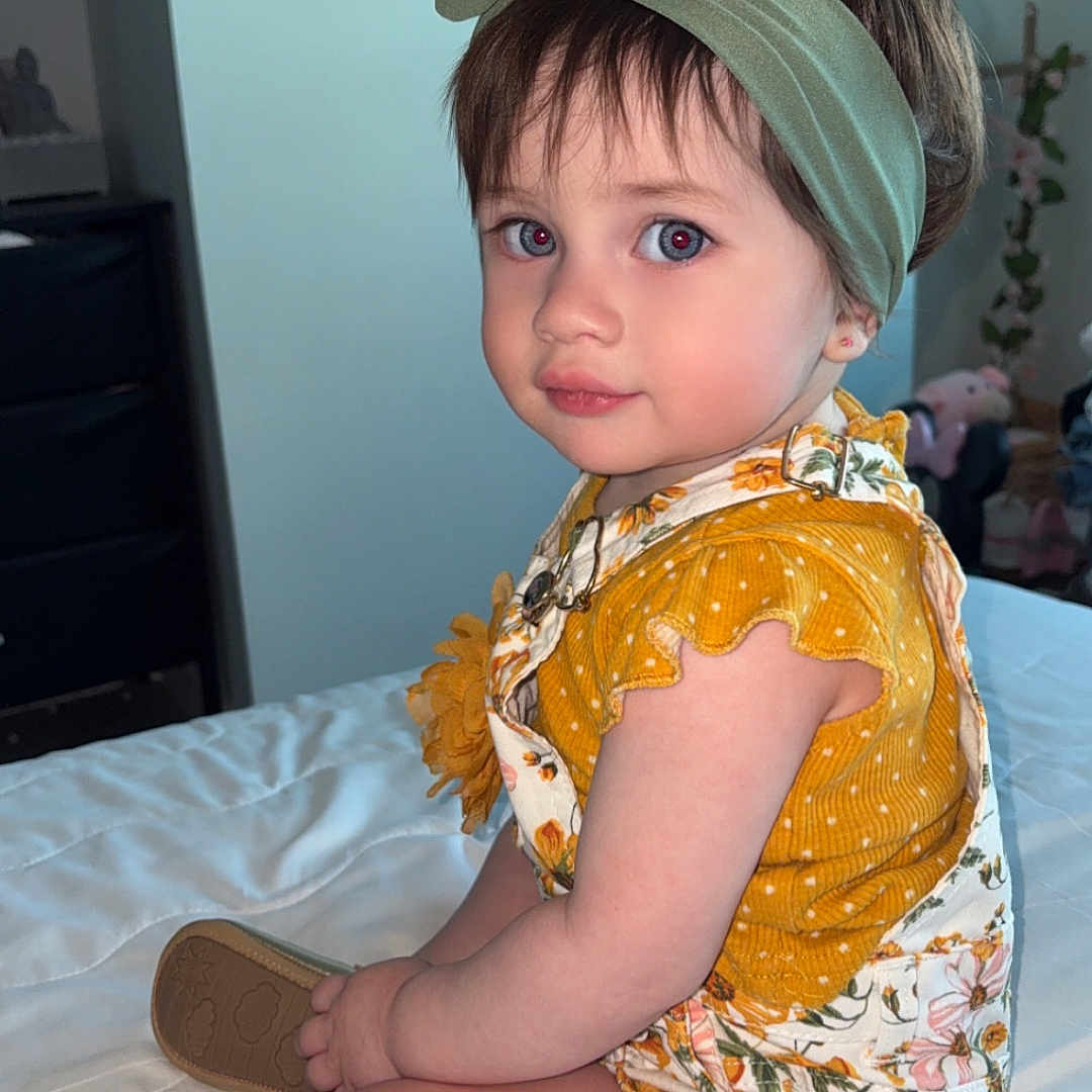 Zaiori joined the competition — help win amazing prizes! baby, bed, child, clothing, cute, face, floral_overalls, footwear, furniture, hair, hand, headband, indoor, person, portrait, sitting, skin, soft_lighting, toddler, yellow_top