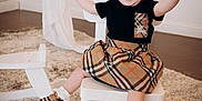 Zaiori is registered to the contest to win money with this photo: toddler, child, smiling, sitting, chair, plaid, skirt, shoes, headband, carpet, indoor, white, furniture, happy, cute, person, fashion, rocking_horse, room, playful