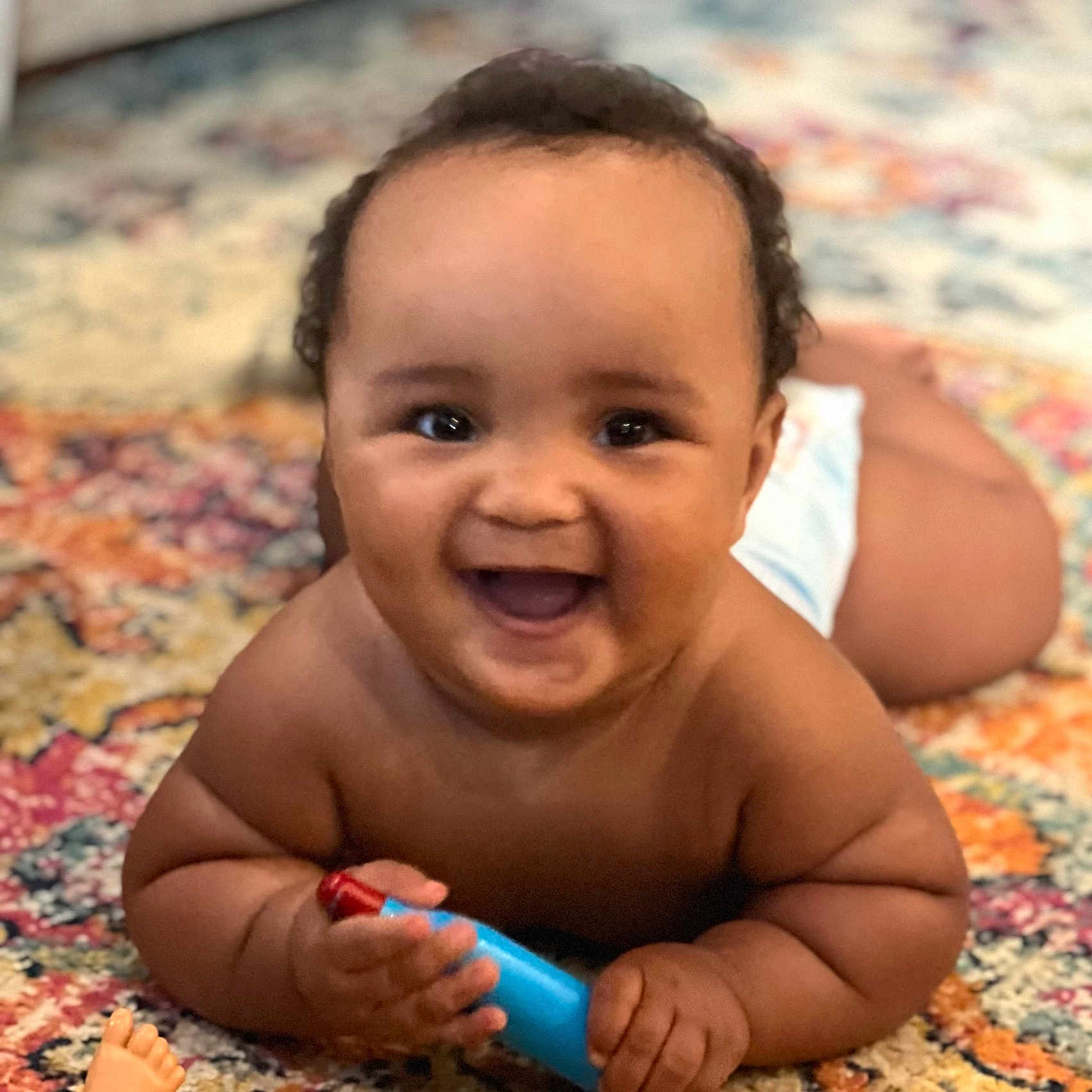 Kashton joined the competition — help win amazing prizes! baby, carpet, child, chubby, cute, diaper, excitement, expression, face, hand, happy, indoors, infant, lying_down, patterned_rug, playful, skin, smiling, toy, young