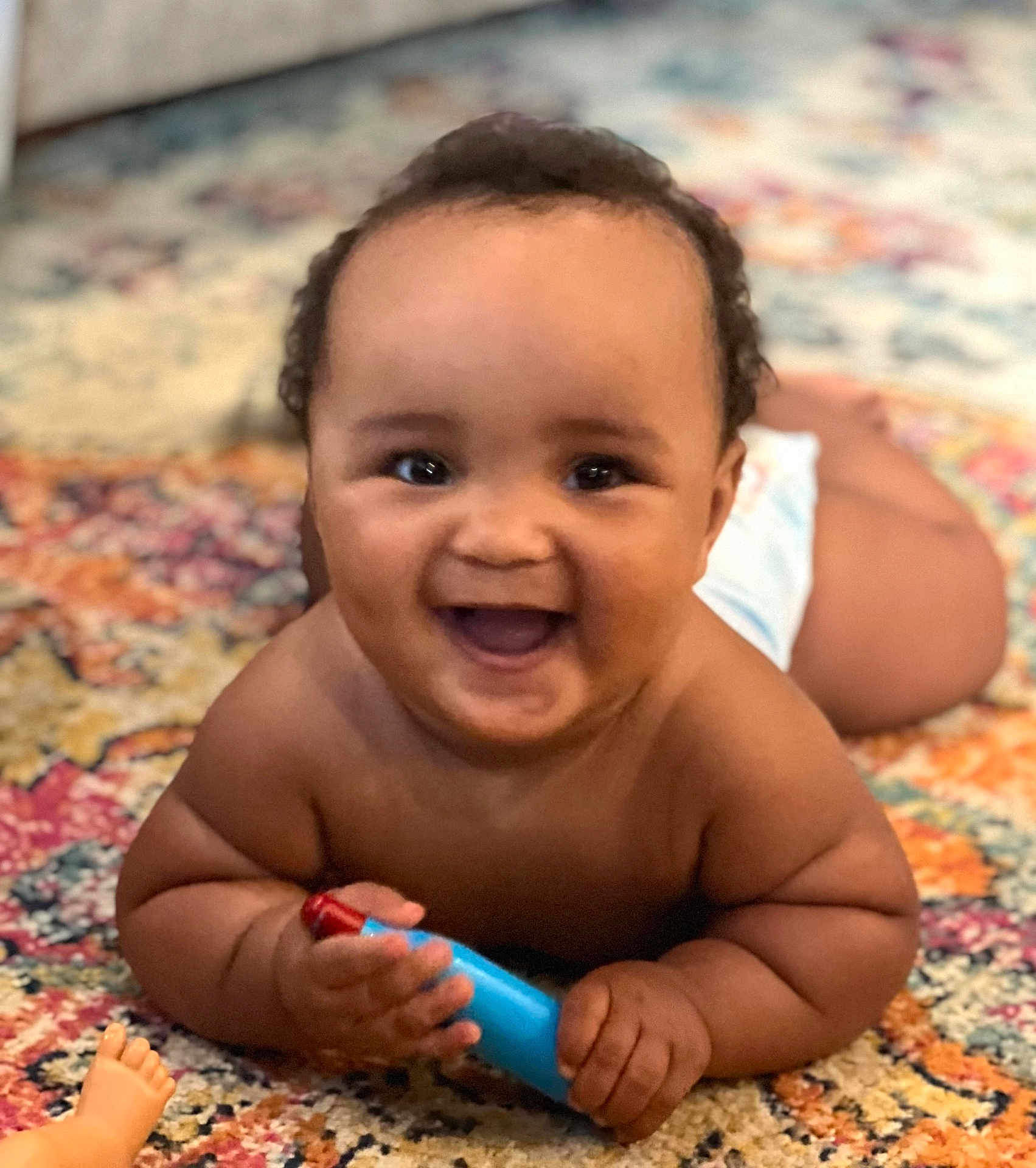 Kashton joined the competition — help win amazing prizes! baby, smiling, happy, infant, toy, diaper, carpet, patterned_rug, cute, child, skin, hand, face, indoors, playful, lying_down, chubby, expression, excitement, young