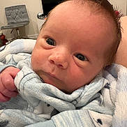 Colt is registered to the contest to win money with this photo: baby, newborn, infant, face, eyes, hand, blanket, blue_clothing, swaddle, cozy, portrait, close_up, hair, skin, indoor, television, chair, sofa, nursery, cute