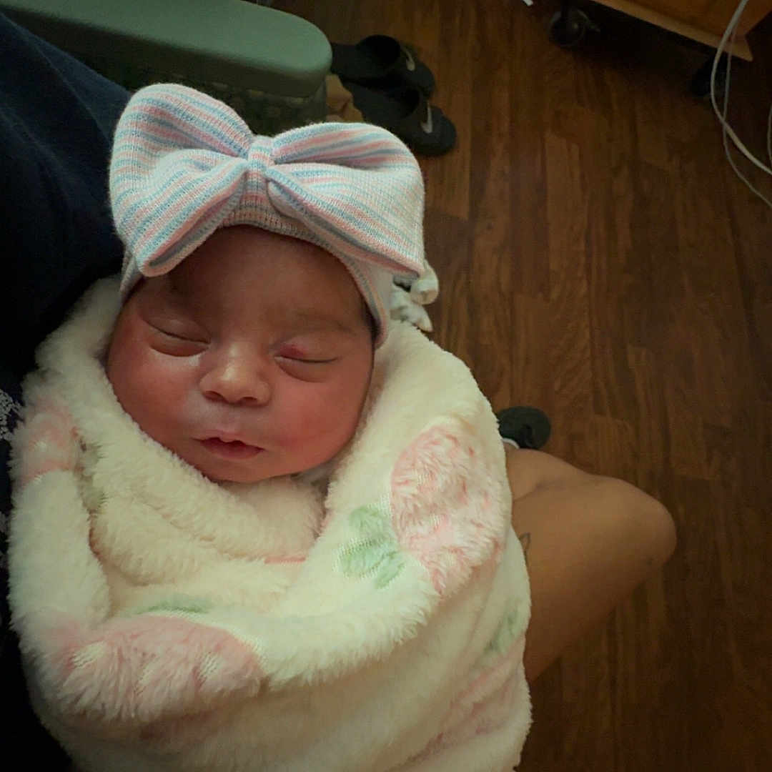 Maylani joined the competition — help win amazing prizes! baby, blanket, bow, burrito, chair, closed_eyes, cozy, face, family_photo, furniture, headband, indoors, infant, newborn, pastel, peaceful, portrait, sleeping, swaddled, wooden_floor
