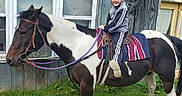 Brytton is registered to the contest to win money with this photo: animal, child, clothing, daylight, fence, fun, grass, helmet, horse, house, outdoor, person, pet, reins, riding, saddle, satellite_dish, smile, window, yard