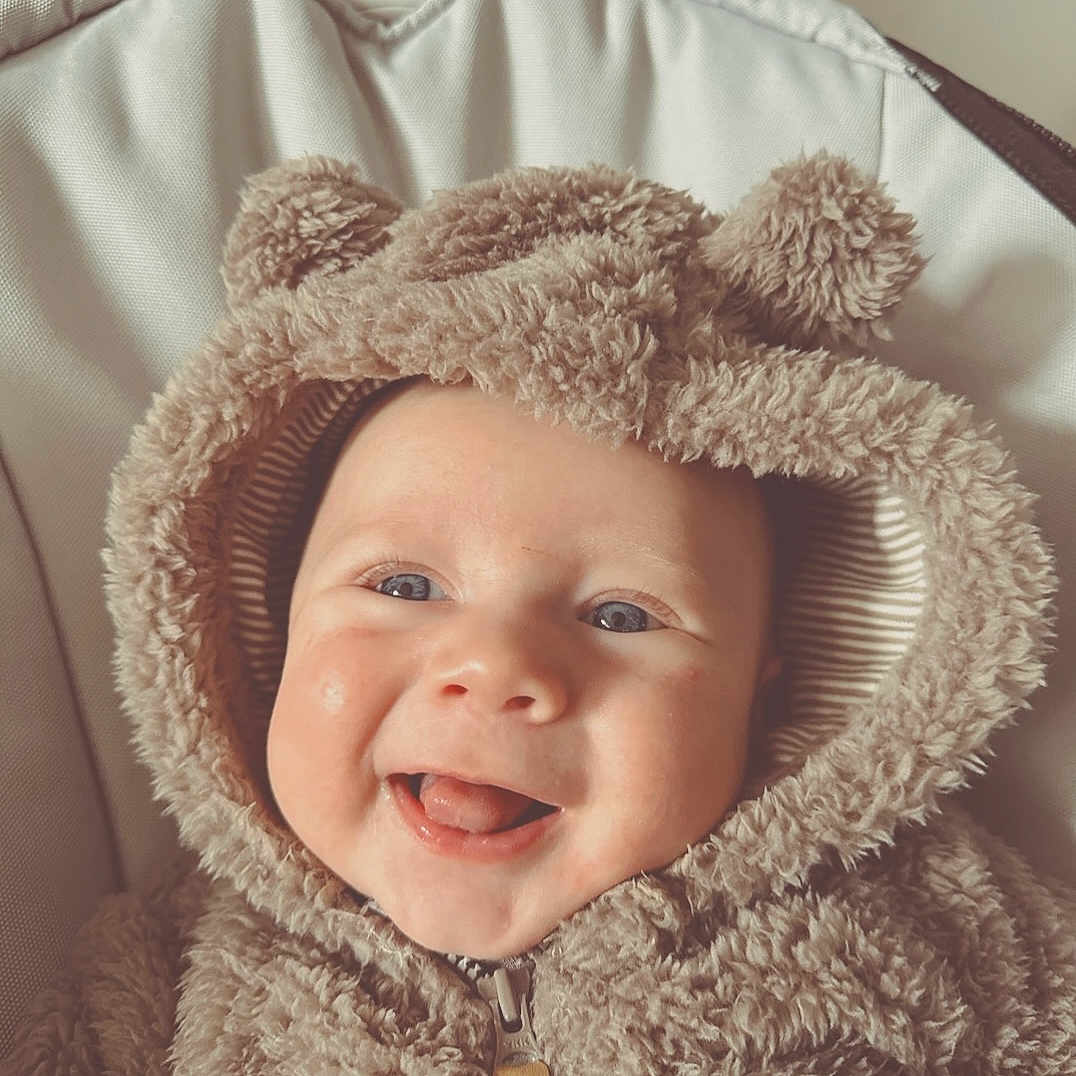Vincenzo is registered to the contest to win money with this photo: baby, babylaughing, blanket, bonnet, clothing, coat, face, happy, hat, head, hood, hoodie, jacket, knitwear, person, photography, portrait, smile, sweater, sweatshirt