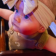Haisley joined the competition — help win amazing prizes! adorable, baby, baby_clothing, bib, child, close_up, colorful, face, fashion, headband, highchair, indoor, infant, large_bow, portrait, restaurant, seated, smiling, warm_lighting, wide_eyed