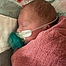 newborn, baby, sleeping, blanket, pink, nasal_cannula, medical_tube, pacifier, face, head, infant, resting, cozy, closeup, indoor, child, person, soft_texture, healthcare, floral_pattern