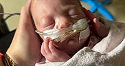 Gracie is registered to the contest to win money with this photo: newborn, baby, infant, sleeping, blanket, hand, hospital, medical_tubes, care, person, healthcare, equipment, closeup, wrapped, soft, peaceful, rest, tiny, pediatric, neonatal