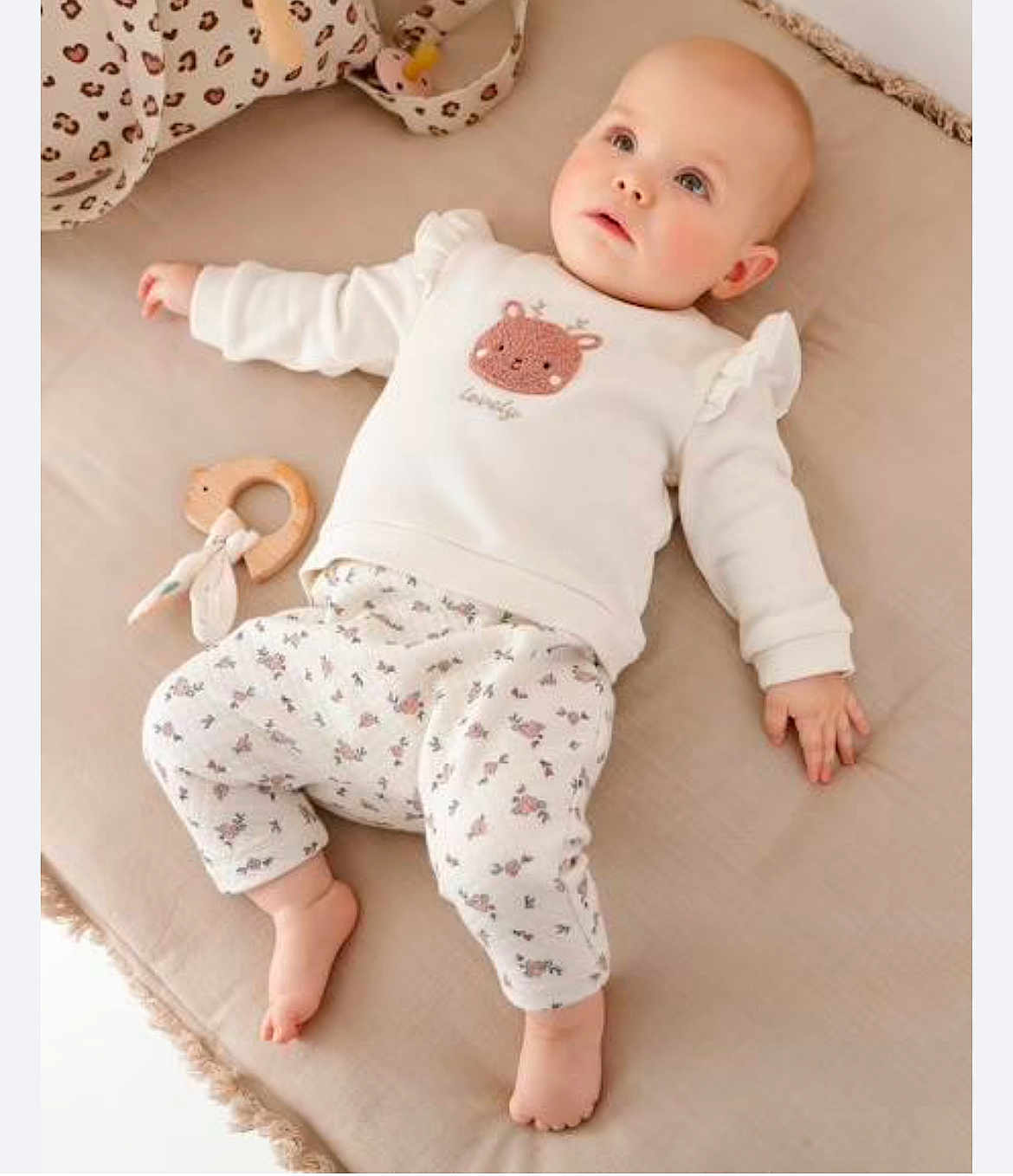 Talia a rejoint le concours — aidez-le/la à gagner de superbes lots ! baby, infant, child, lying_down, cushion, toy, wooden_toy, clothing, white_clothes, patterned_pants, deer_design, soft_texture, indoors, cute, gazing_up, barefoot, pink_cheeks, comfortable, relaxed, nursery
