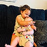 affection, baby, black_couch, black_sock, child, clothing, couch, cushion, cute, home, hug, indoor, kiss, matching_outfits, person, playful, seated, siblings, smile, toddler