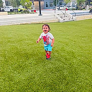 Bryant is registered to the contest to win money with this photo: toddler, child, grass, outdoor, happy, running, spiderman, tshirt, shorts, sneakers, urban, building, tree, car, stairs, lamp_post, sidewalk, daylight, play, person