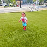 building, car, child, daylight, grass, happy, lamp_post, outdoor, person, play, running, shorts, sidewalk, sneakers, spiderman, stairs, toddler, tree, tshirt, urban