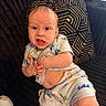baby, child, clothing, couch, cute, expression, face, footwear, hand, home, indoor, infant, pajamas, pattern, person, pillow, sitting, skin, texture, young