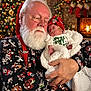baby, christmas, santa_claus, sleeping, holiday, festive, beard, glasses, red_hat, blanket, fireplace, stockings, tree, decorations, warmth, indoors, cozy, holding, face, person