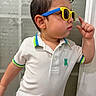 child, toddler, portrait, side_profile, sunglasses, fashion, posing, serious, indoor, bathroom, shirt, polo_shirt, white_clothing, blue, yellow, short_hair, wet_hair, hand_gesture, standing, photography
