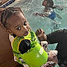 toddler, child, pool, water, floatation_device, swimming, adult_hand, braided_hair, sitting, safety, edge, casual, indoor_pool, clothing, play, fun, young_child, person, water_activity, support