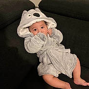 Klei participe au concours pour gagner de l'argent avec cette photo : baby, child, infant, bathrobe, hood, animal_hood, grey, couch, sofa, black, indoor, cute, cozy, relaxed, person, face, eyes, legs, barefoot, furniture