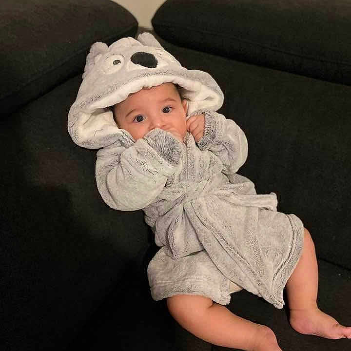 Klei participe au concours pour gagner de l'argent avec cette photo : animal_hood, baby, barefoot, bathrobe, black, child, couch, cozy, cute, eyes, face, furniture, grey, hood, indoor, infant, legs, person, relaxed, sofa