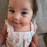 Jade is registered to the contest to win money with this photo: baby, infant, child, portrait, face, smile, eyes, pink_clothing, striped, cute, sitting, hand, couch, fabric, skin, hair, indoors, closeup, young, person