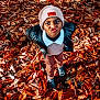 Arthur a rejoint le concours — aidez-le/la à gagner de superbes lots ! child, kid, beanie, hat, leather_jacket, sweater, pants, shoes, autumn_leaves, fall, foliage, outdoor, portrait, looking_up, funny_face, playful, standing, ground_cover, seasonal, young_child