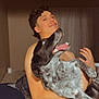 man, shirtless, dog, black_and_white_dog, indoor, bedroom, bed, curtains, smiling, pet, holding, joyful, carpet, blanket, pillow, human, canine, animal, tongue_out, happy