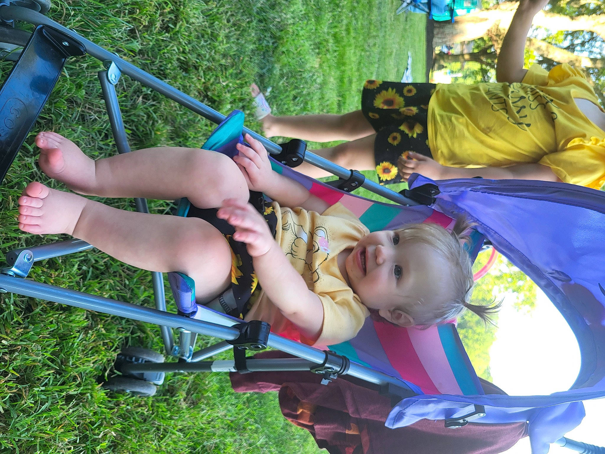 Phoenix is registered to the contest to win money with this photo: baby, child, city, electric_blue, event, fun, grass, human_leg, leisure, outdoor_play_equipment, person, photograph, plant, playground, recreation, shorts, smile, swing, thigh, toddler