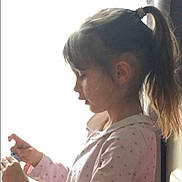 Lena a rejoint le concours — aidez-le/la à gagner de superbes lots ! child, girl, profile, pony_tail, indoor, window, side_view, long_hair, light, shadow, shirt, focused, young, person, casual_clothing, natural_light, silhouette, contemplative, hands, soft