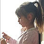 child, girl, profile, pony_tail, indoor, window, side_view, long_hair, light, shadow, shirt, focused, young, person, casual_clothing, natural_light, silhouette, contemplative, hands, soft