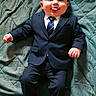 baby, child, infant, suit, tie, formalwear, navy_blue, portrait, lying_down, blanket, teal, smiling, tongue_out, bald, face, hands, shoes, indoor, funny, photography