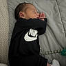 baby, sleeping, infant, bed, blanket, gray, black_clothing, nike, socks, curled_up, peaceful, nap, portrait, indoors, bedding, toy, soft, cozy, face, hands