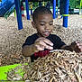 Kenji is registered to the contest to win money with this photo: child, boy, playground, wood_chips, black_shirt, puma, playing, happy, outdoor, daylight, slide, climbing_structure, green, blue, wood, nature, smiling, hands, fun, park