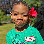 Kenji joined the competition — help win amazing prizes! child, boy, smile, face, green_tshirt, marvel_logo, flower, outdoor, nature, sunlight, grass, tree, happy, portrait, casual_clothing, short_hair, daylight, person, cute, playful