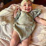 baby, infant, smile, headband, plush_toy, bunny, blanket, soft_texture, happy, cute, lying_down, child, indoor, warm_light, green_outfit, cozy, portrait, baby_girl, toddler, candid