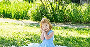 Oakley joined the competition — help win amazing prizes! child, girl, blue_dress, smiling, sitting, blanket, grass, outdoor, sunlight, greenery, tree, nature, portrait, happy, curly_hair, daylight, garden, young, playful, cute
