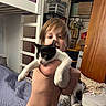 Cow joined the competition — help win amazing prizes! child, cat, black_and_white_cat, person, pet, holding, bedroom, bed, blanket, wardrobe, closet, clothing, indoor, portrait, candid, playful, smiling, animal, kitten, home