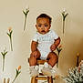 Silas joined the competition — help win amazing prizes! toddler, child, baby, wooden_stool, onesie, bunny_slippers, easter, tulips, flowers, woven_bunny, basket, indoor, cute, sitting, decor, plant, spring, face, person, footwear